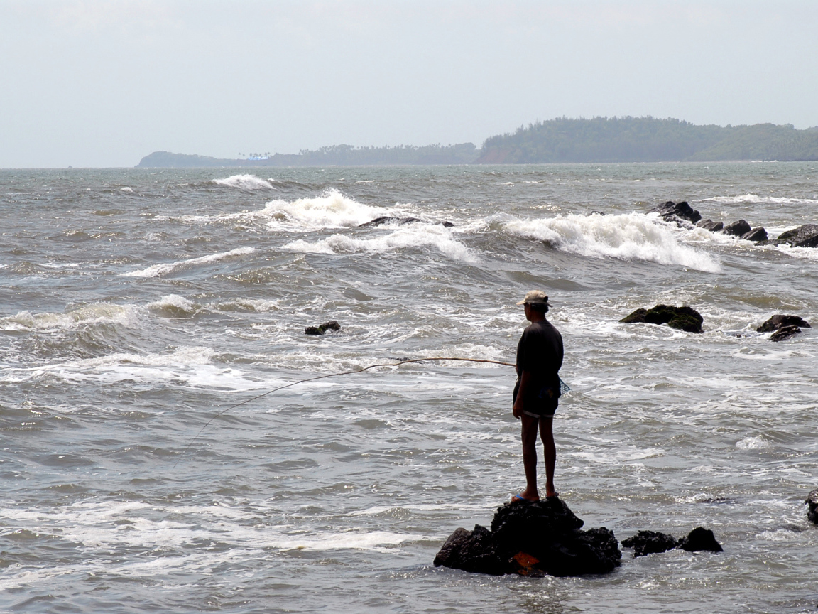 Мужчина ловит рыбу в Гоа