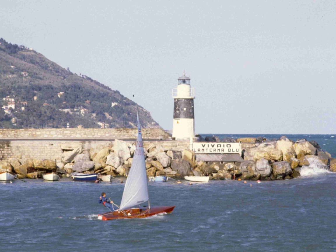 Лодка на фоне маяка на курорте Империя, Италия