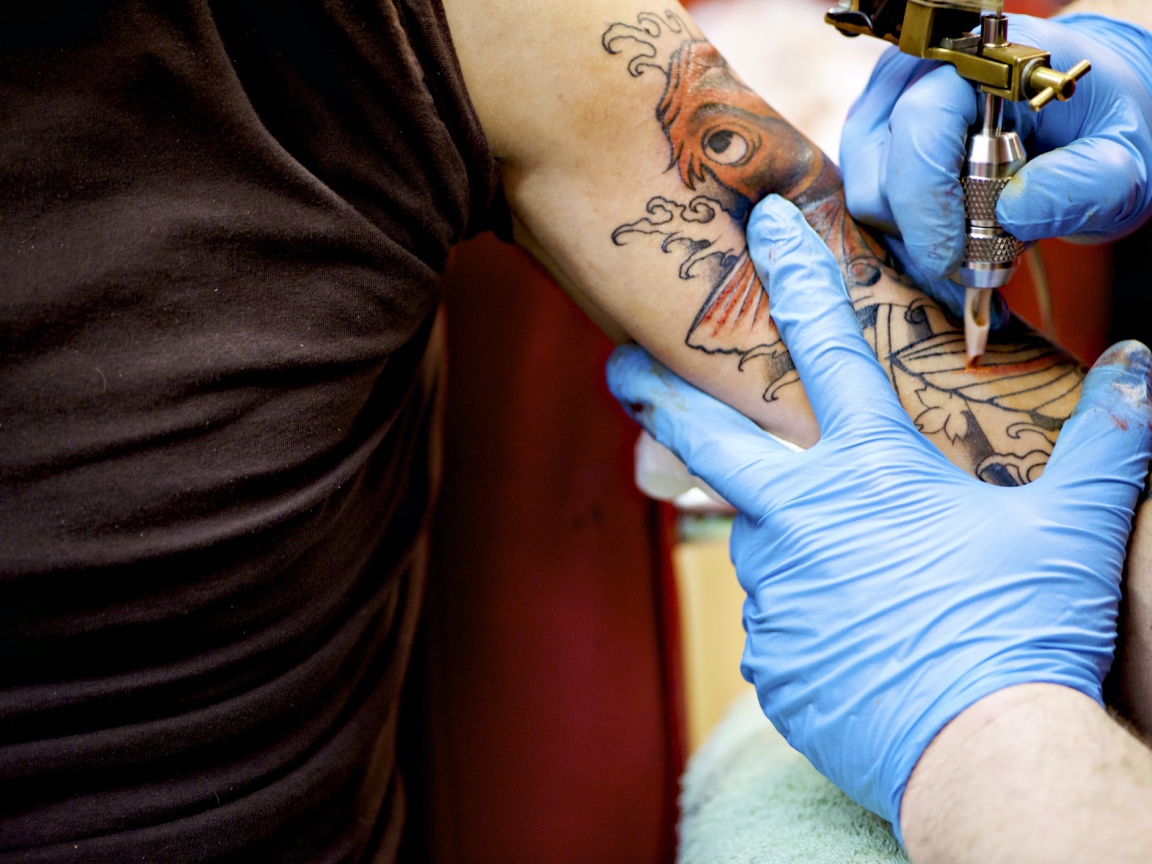 Девушке делают татуировку