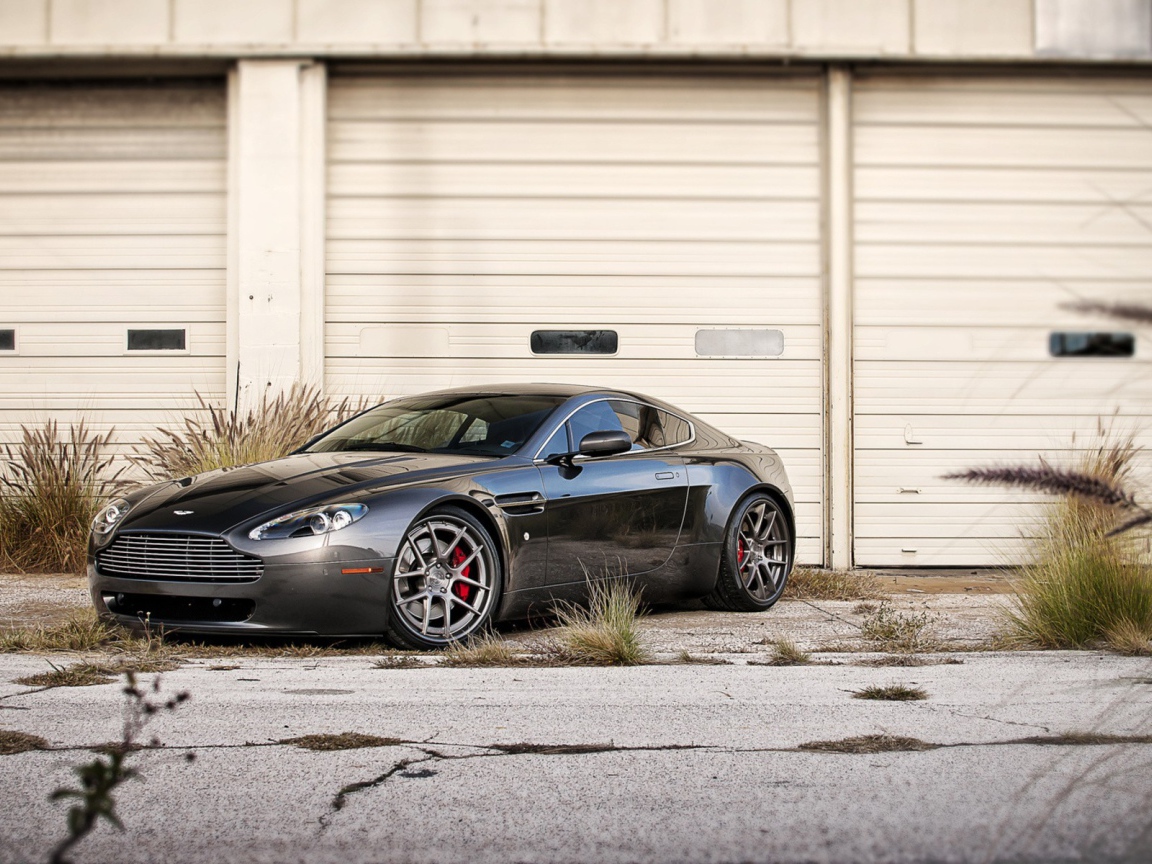 Черный Aston Martin в ворот белого ангара