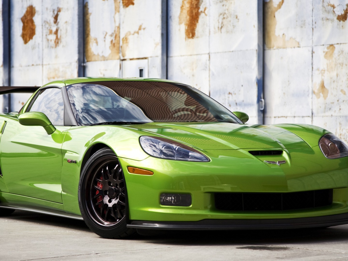 Зеленый Chevrolet Corvette на фоне стены