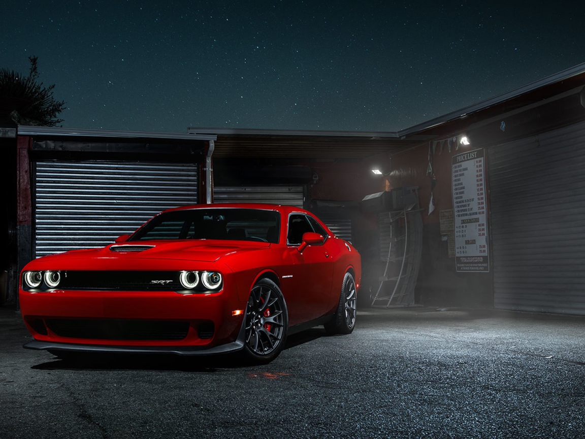 Красный Dodge Challenger Hellcat у гаража