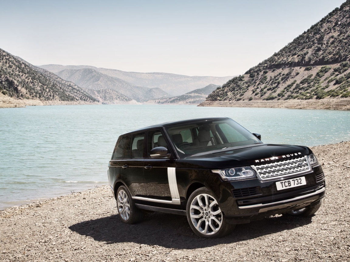Черный Range Rover на берегу водоема