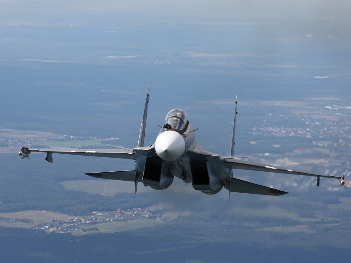 Самолет СУ-27 летит над городом