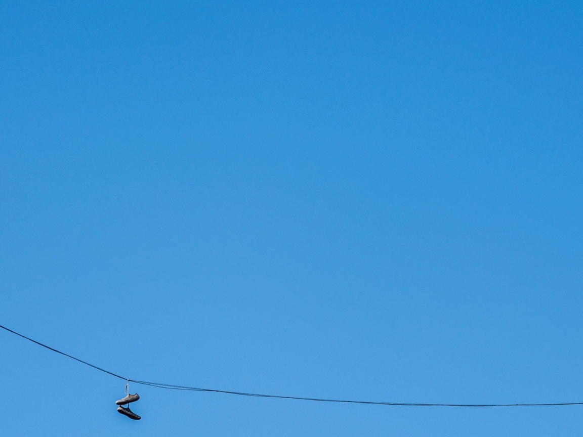 Кеды висят на проводе на фоне голубого неба