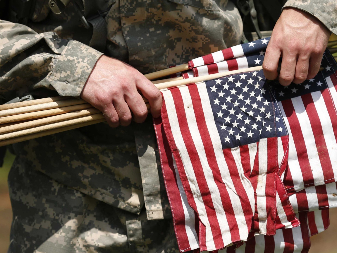 Солдат держит в руке флаги США