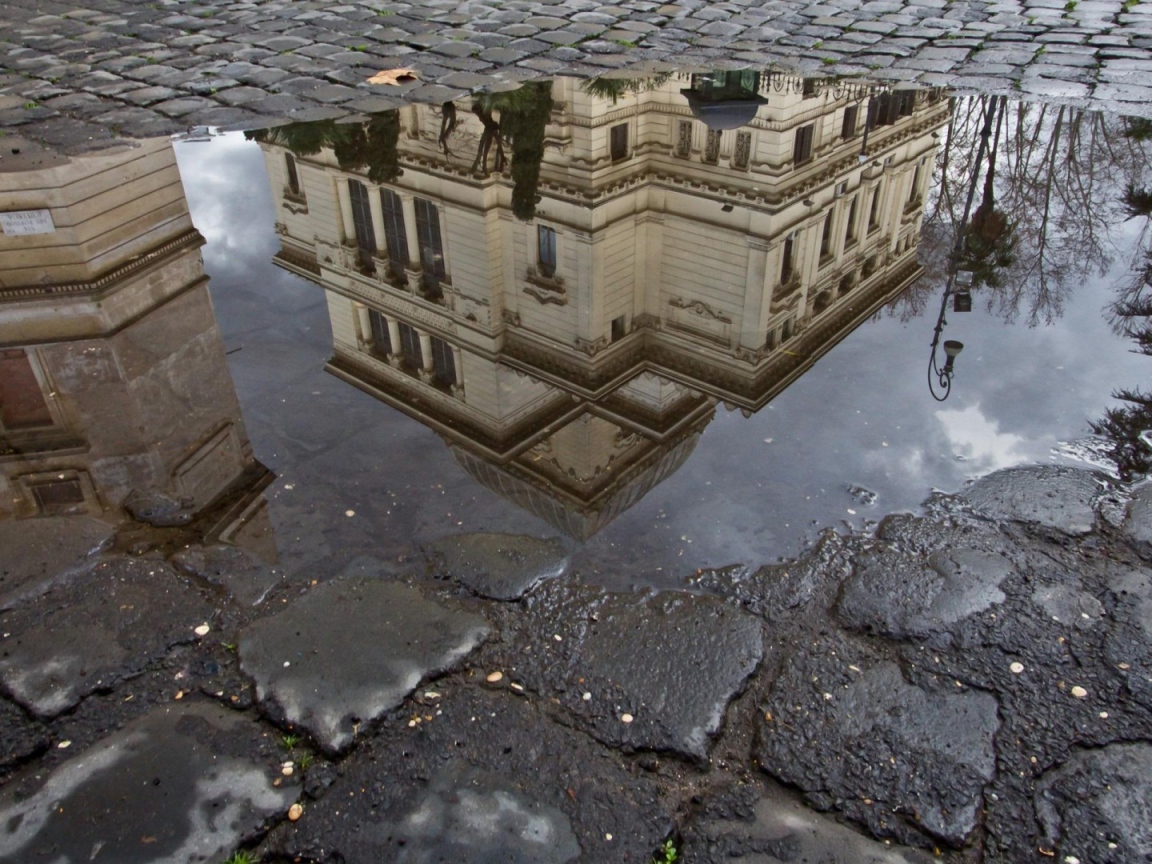 Отражение городского здания в луже
