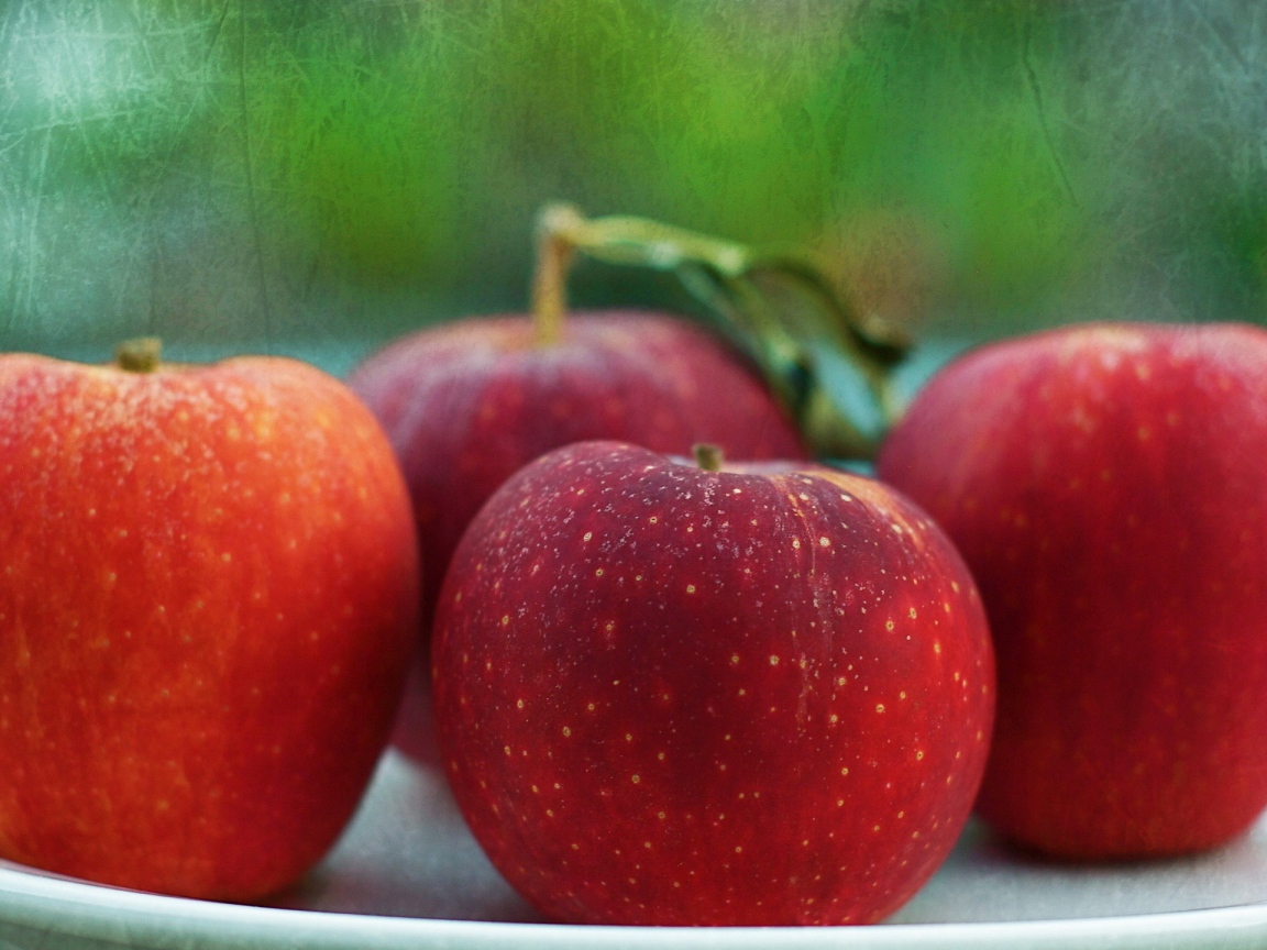 Четыре красных яблока на тарелке