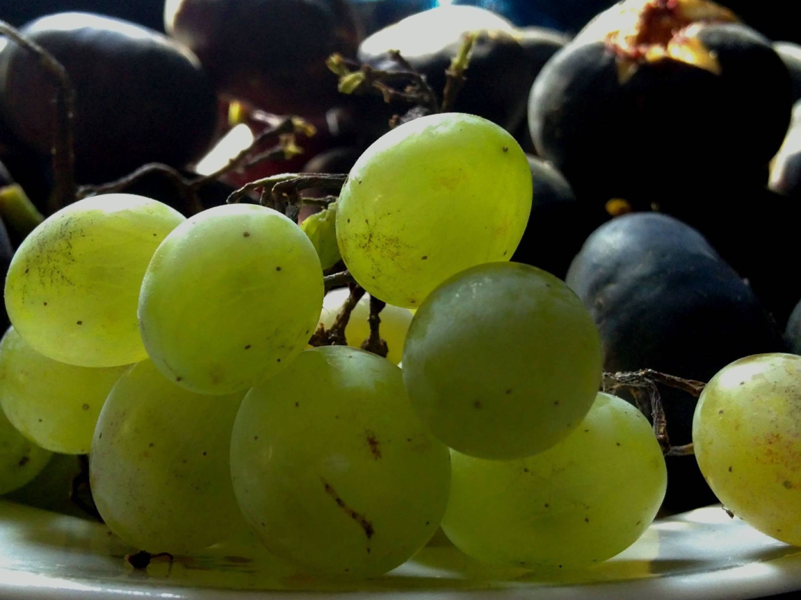 Крупный белый и черный виноград на тарелке