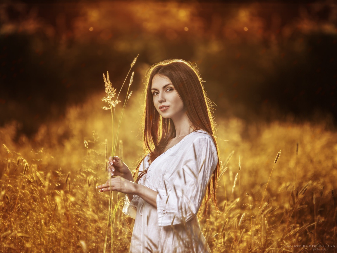 Девушка в белом платье держит в руке колоски