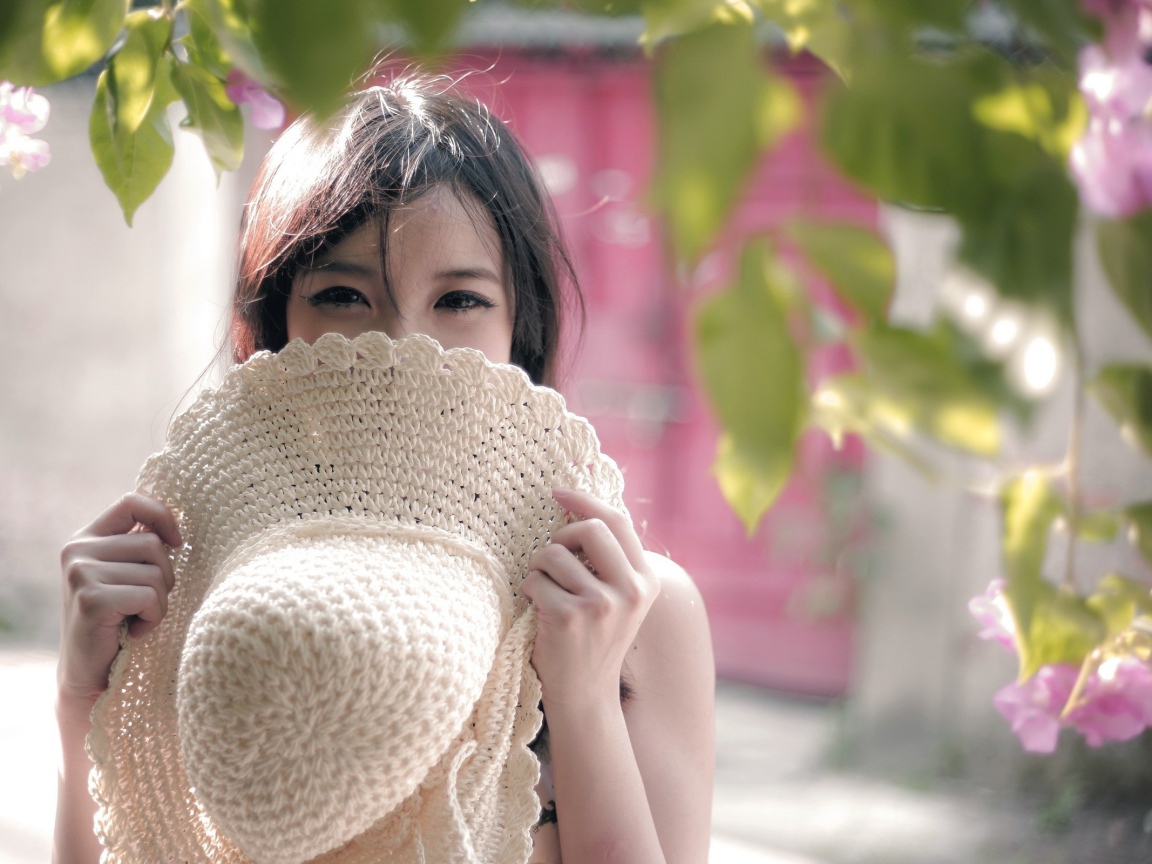 Азиатская девушка прикрыла лицо шляпой