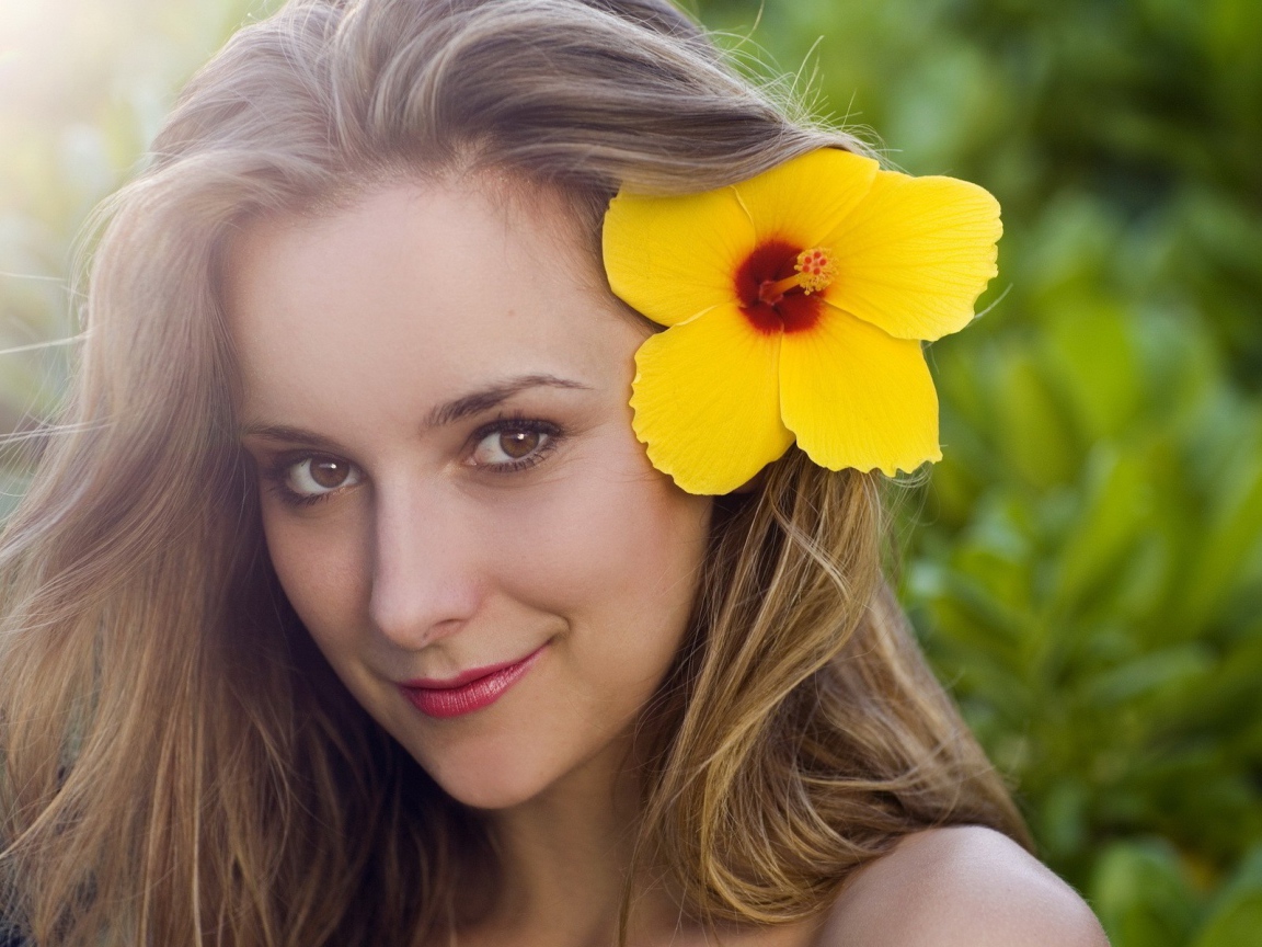 Большой желтый цветок в волосах у девушки