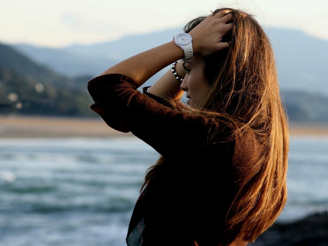 Шатенка с длинными волосами поправляет прическу