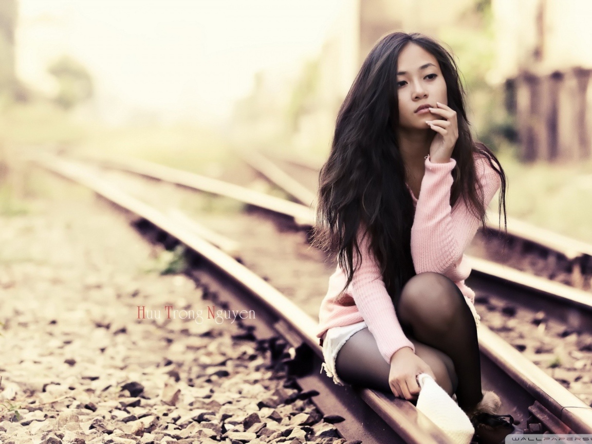 Брюнетка сидит на холодных рельсах