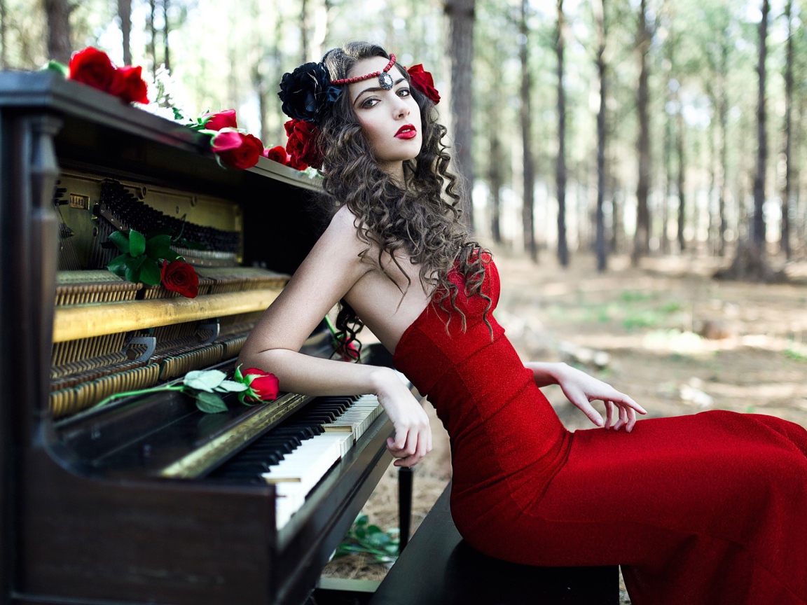 Девушка в красном платье сидит у пианино