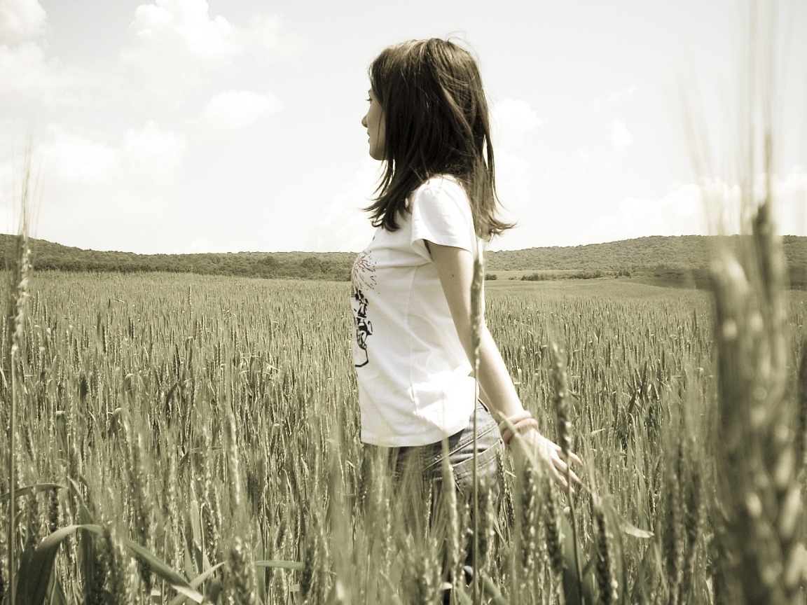 Девушка в белой футболке гуляет по пшеничному полю