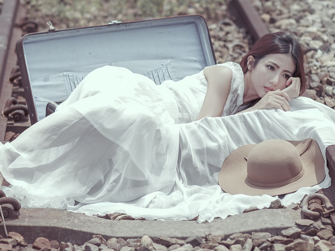 Девушка лежит в чемодане на рельсах