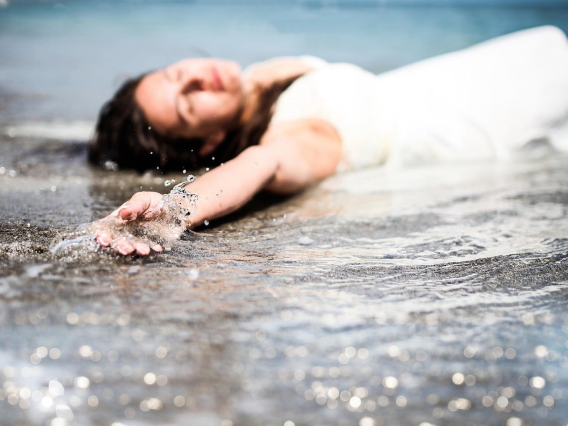 Девушка лежит в волне прибоя