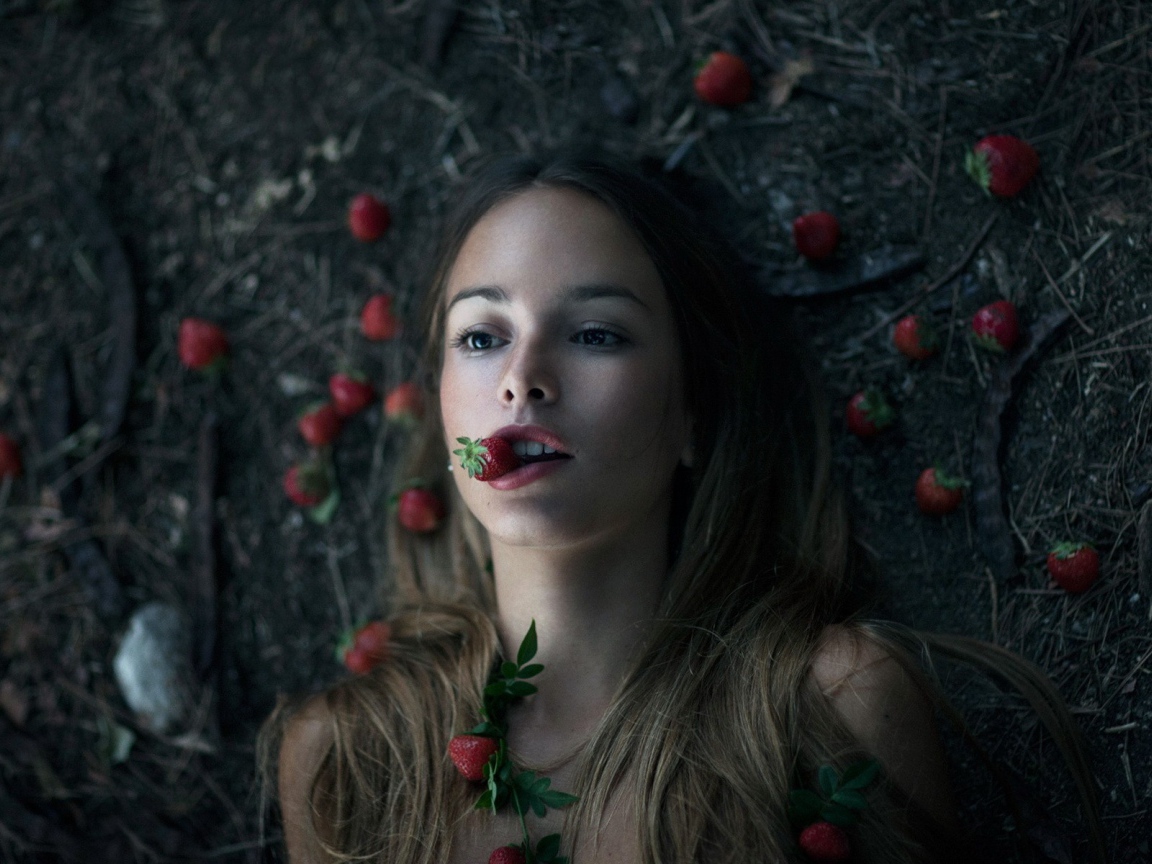 Девушка лежит на земле среди клубники