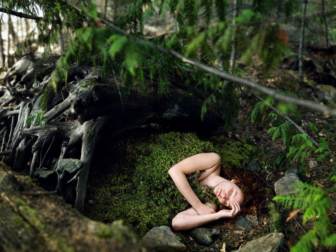 Девушка спит укрывшись мхом в лесу