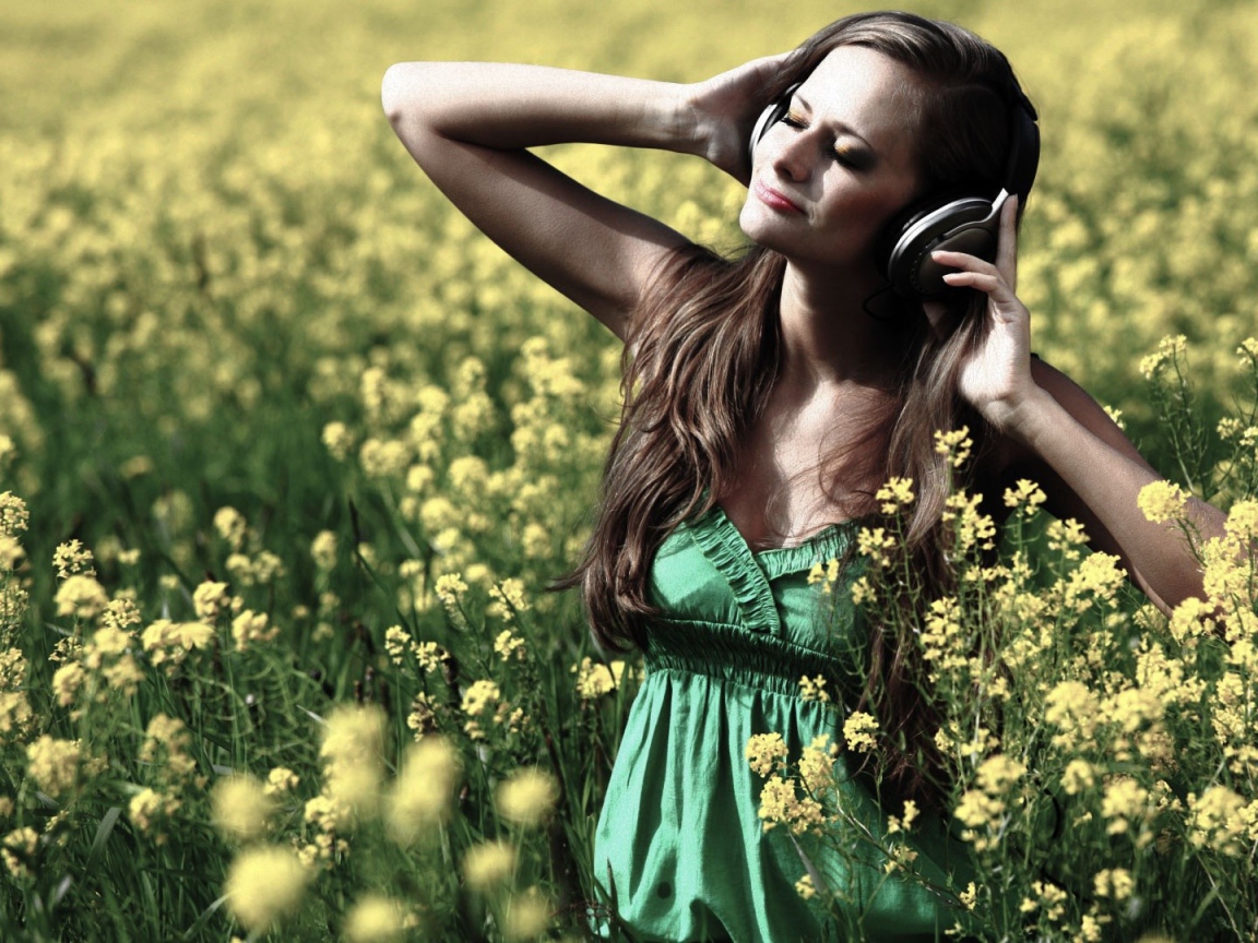 Девушка стоит среди цветов в наушниках