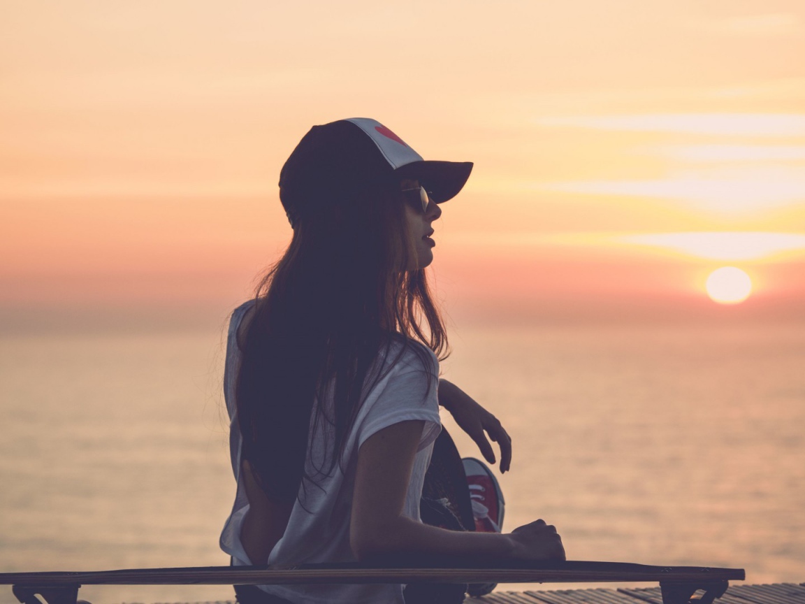 Девушка смотрит на закат на пляже