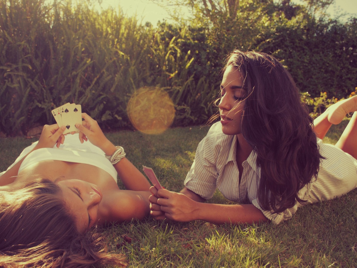 Девушки играют в карты на газоне