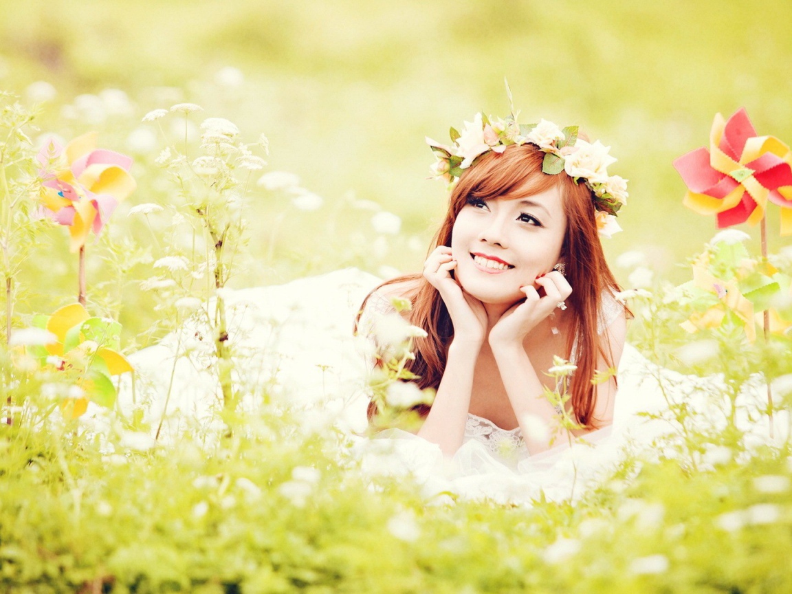 Рыжая японская девушка лежит в поле цветов