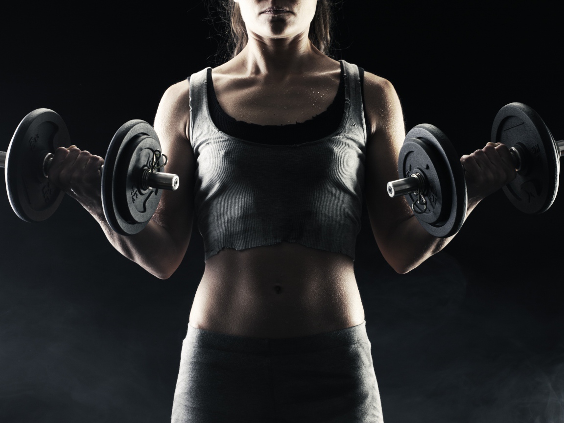 Спортивная девушка с гантелями в руках