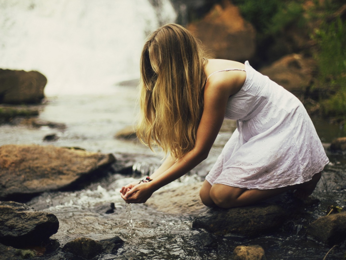 Девушка черпает воду из ручья