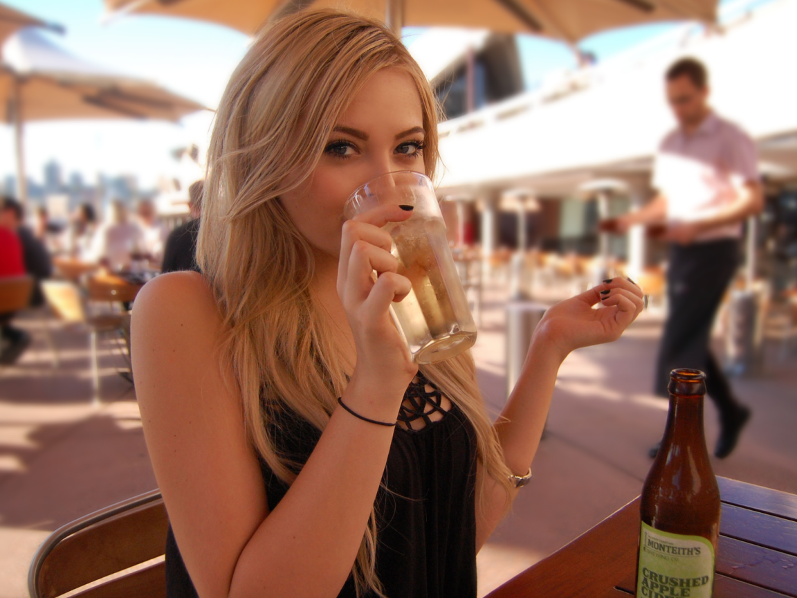 Девушка пьет из стакана в кафе