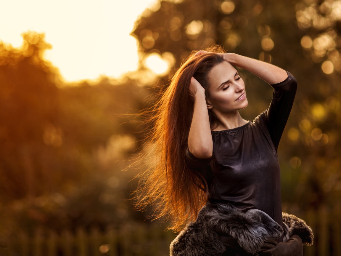 Девушка в черном платье поправляет прическу, портрет