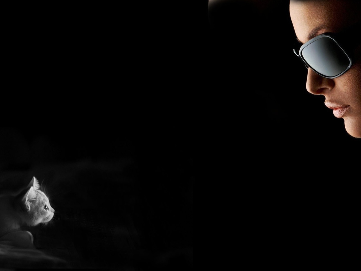 Девушка смотрит на котенка, черный фон