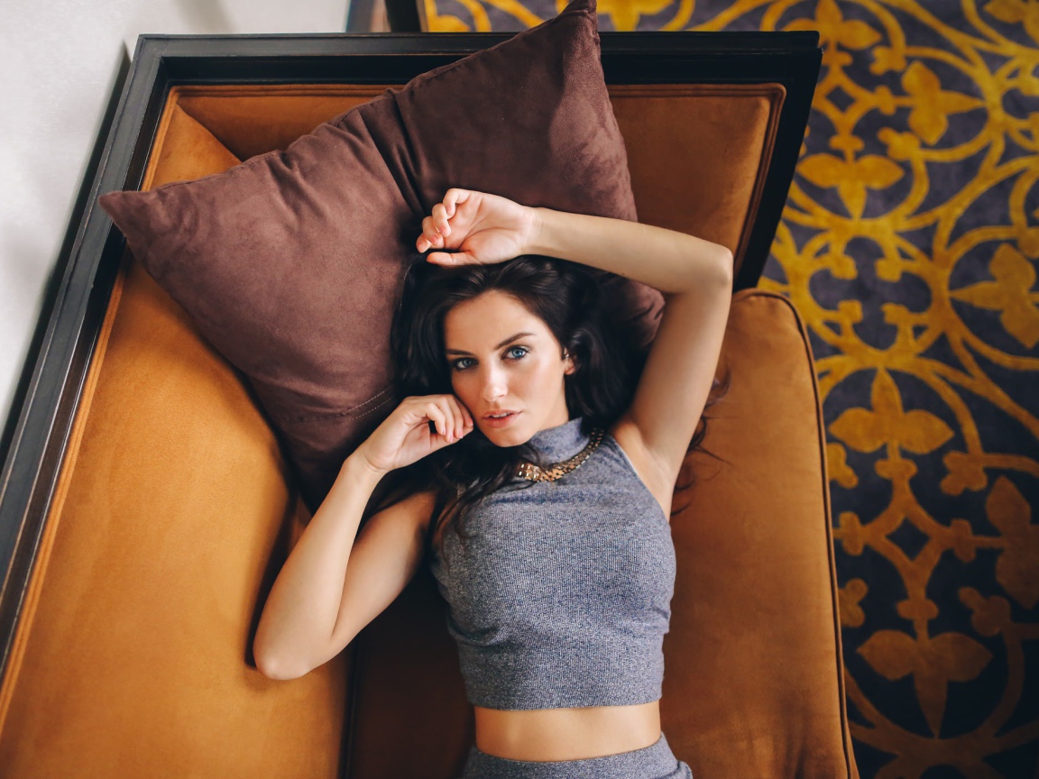 Модель Aurela Skandaj лежит на диване