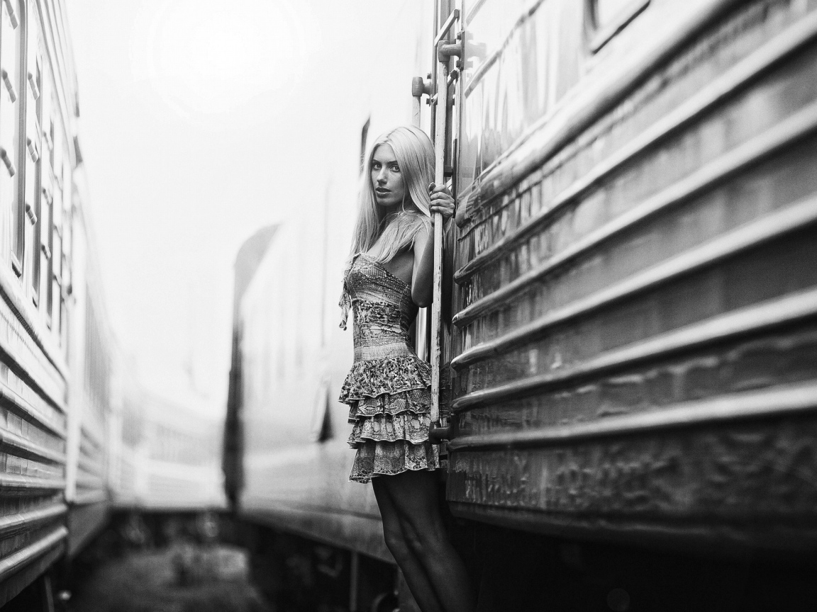 Модель стоит у входа в вагон, черно белое фото