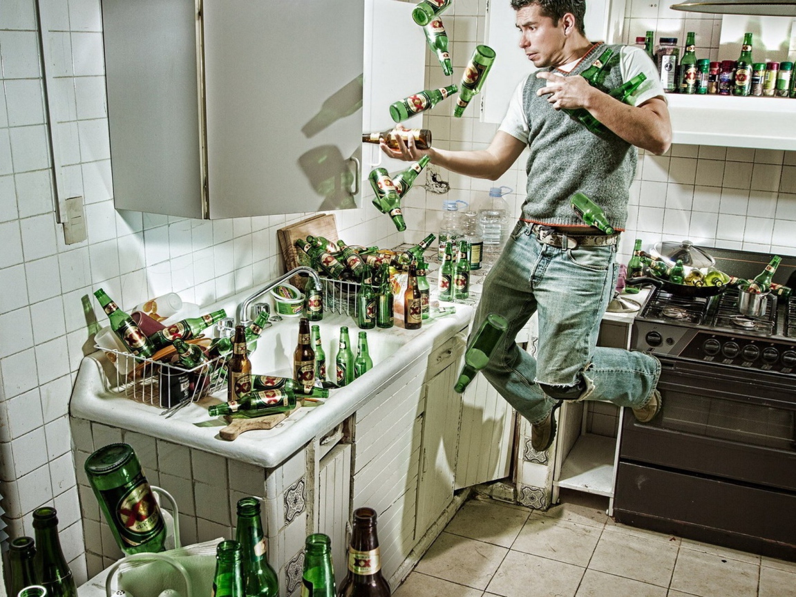 Мужчина среди бутылок пива на кухне