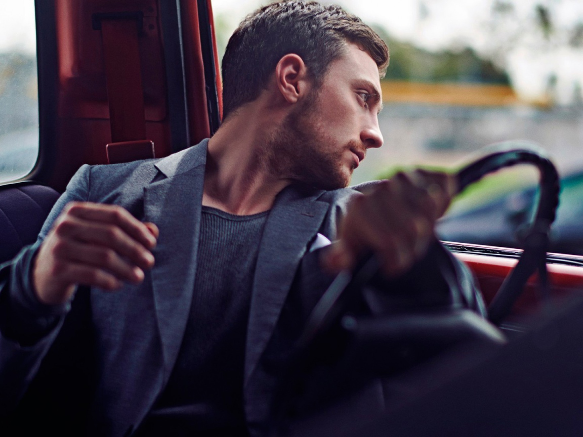 Мужчина за рулем смотрит в окно автомобиля