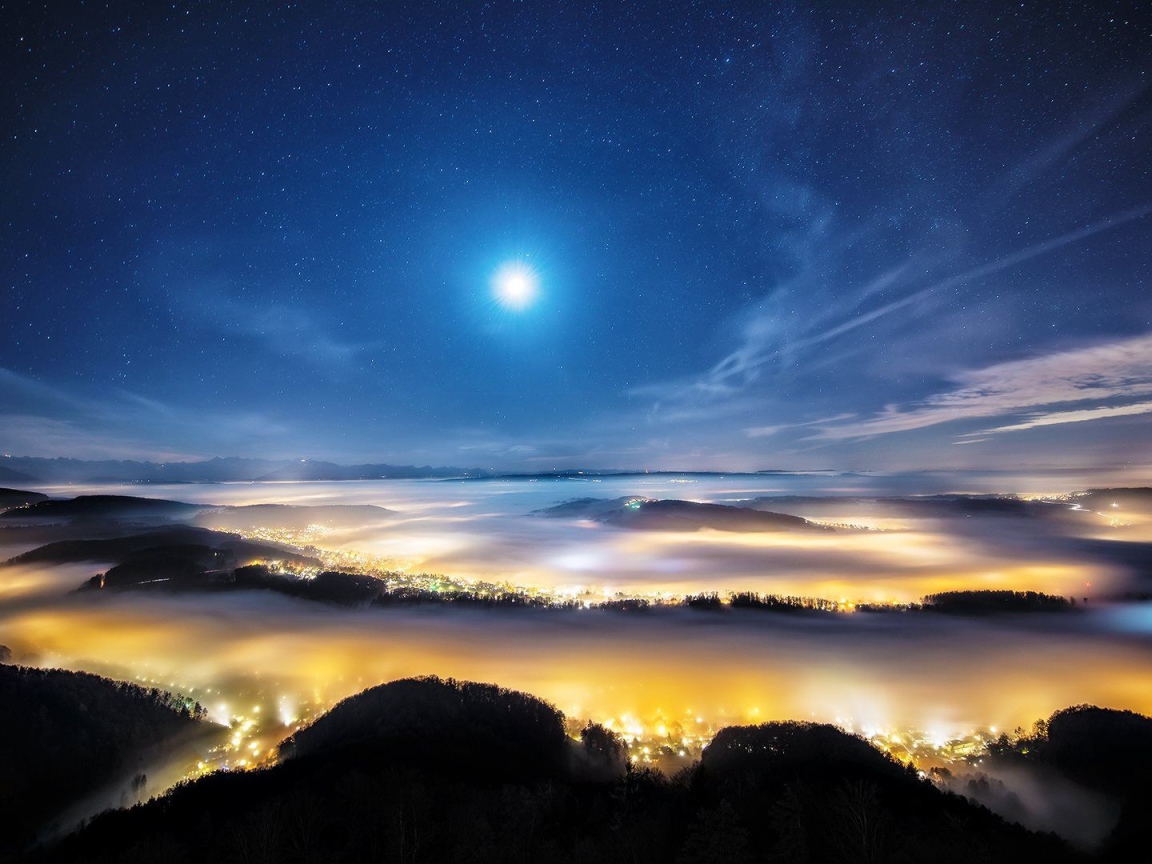 Ночной город в долине под покровом тумана