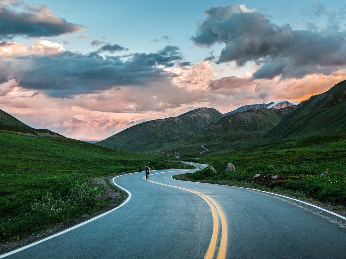 Одинокий путник на шоссе среди гор