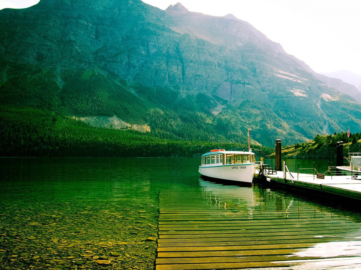 Лодка у причала на зеленой воде горного озера