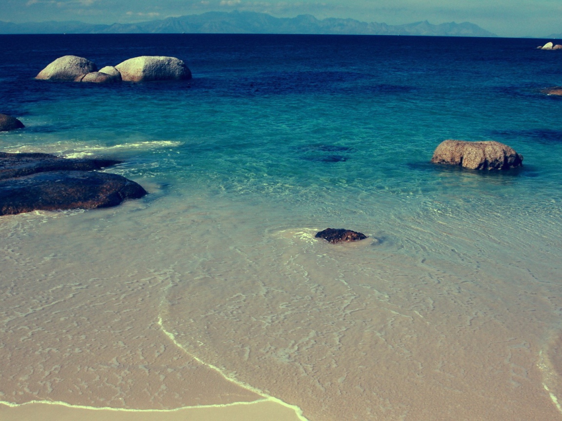 Камни в синей воде у берега моря
