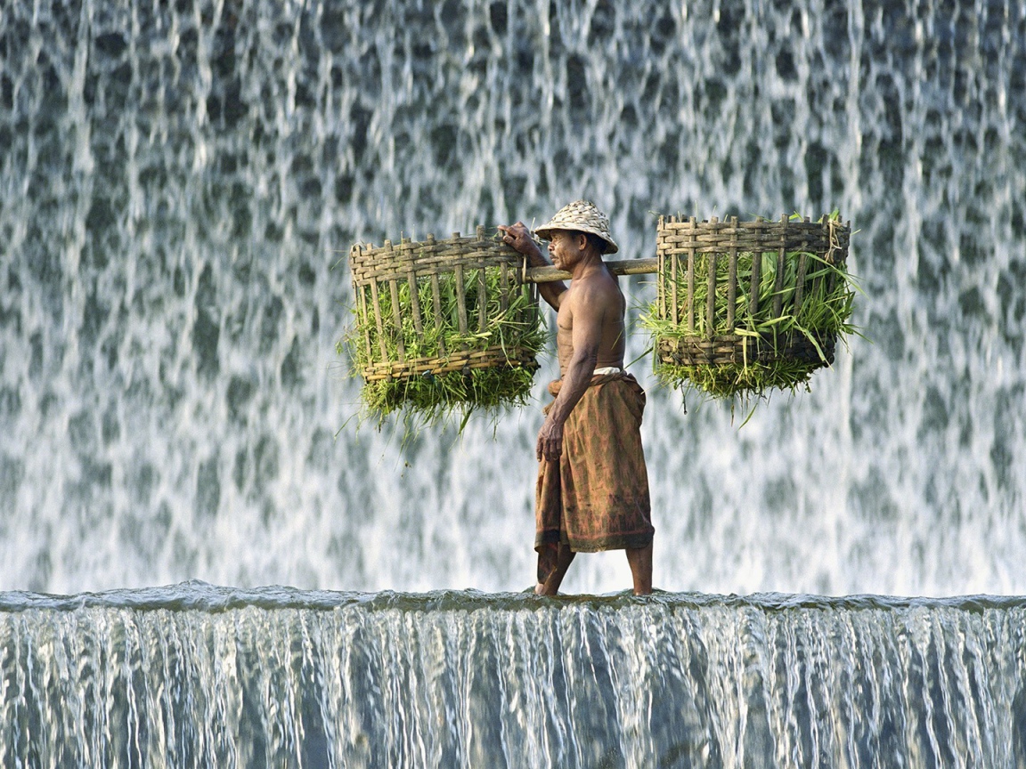 Крестьянин с корзинами идет по водопаду