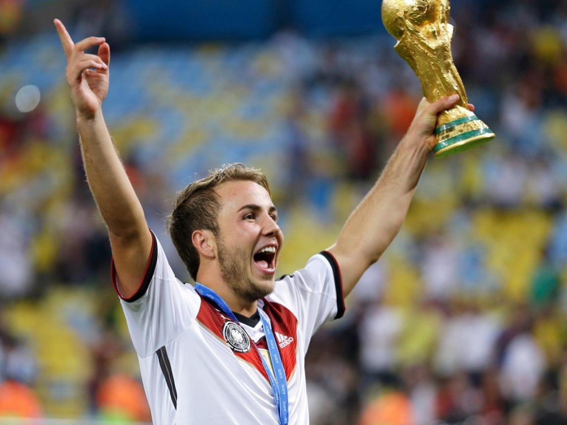 Немецкий футболист Марио Гётце держит в руке кубок