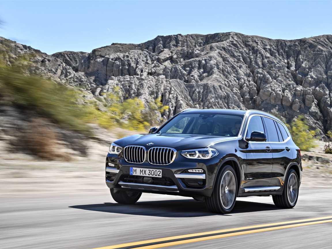 Черный красивый автомобиль BMW X3, 2018 на фоне гор