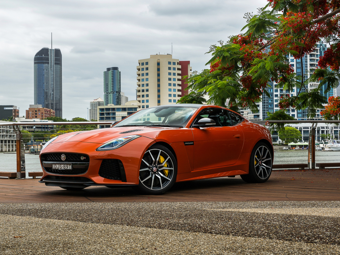 Оранжевый автомобиль Jaguar F-Type на фоне небоскребов 
