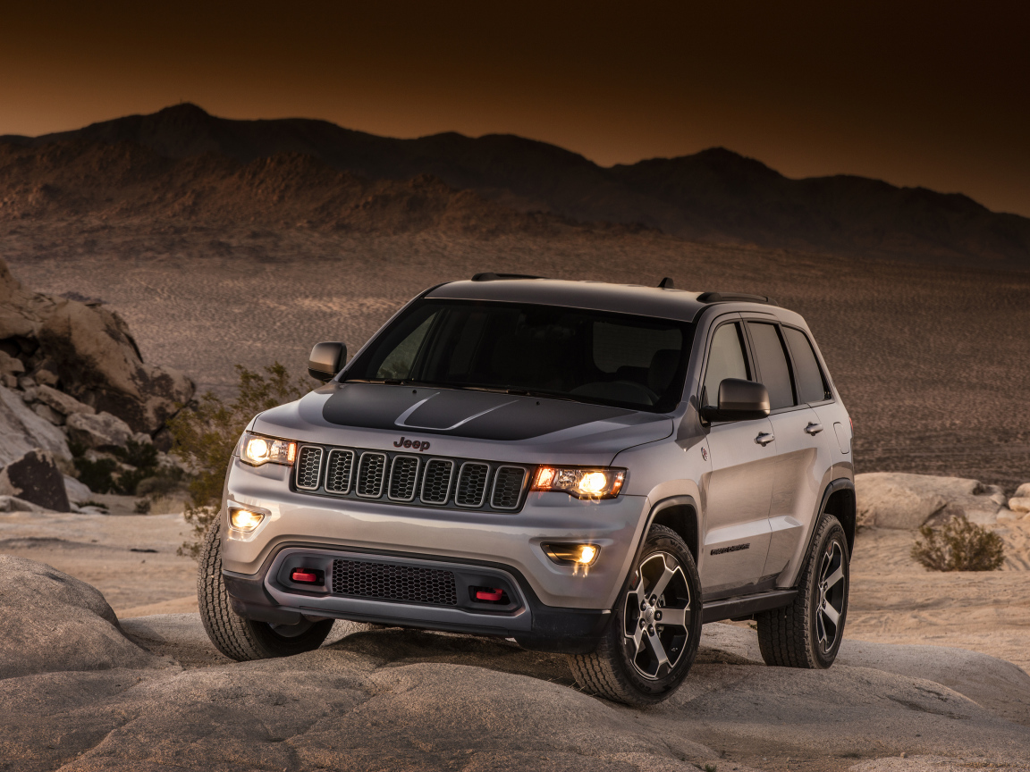 Серебристый внедорожник Jeep Grand Cherokee в пустыне 