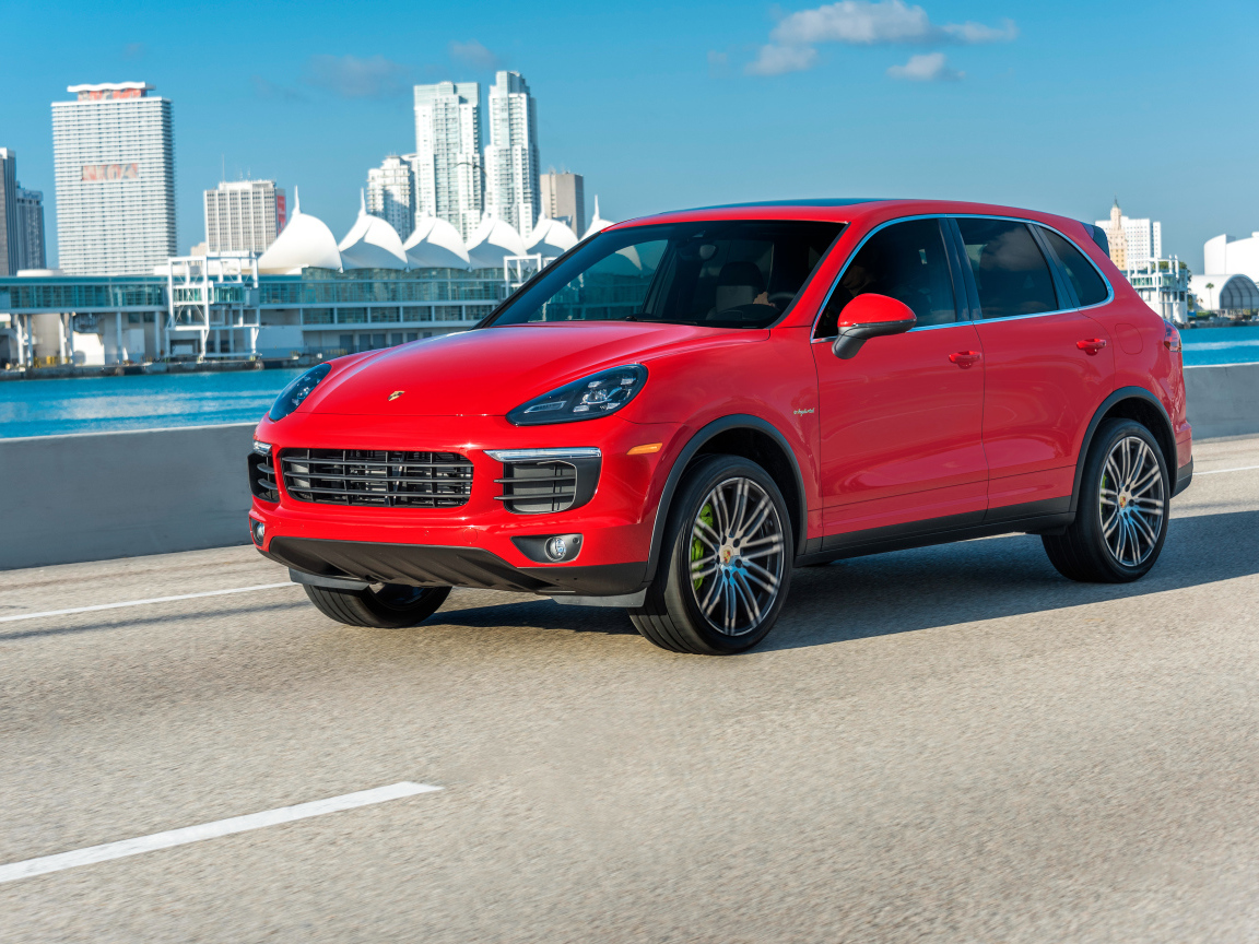 Красный автомобиль Porsche Cayenne на фоне города 