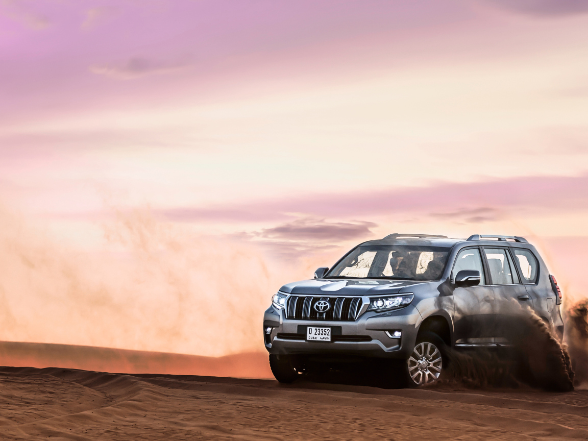 Серебристый внедорожник Toyota Land Cruiser Prado, 2018 едет по песку