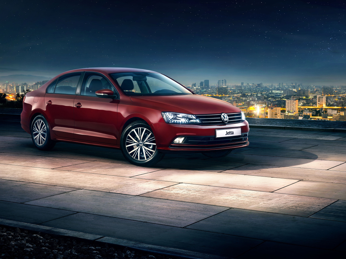 Красный автомобиль Volkswagen Jetta на фоне ночного города