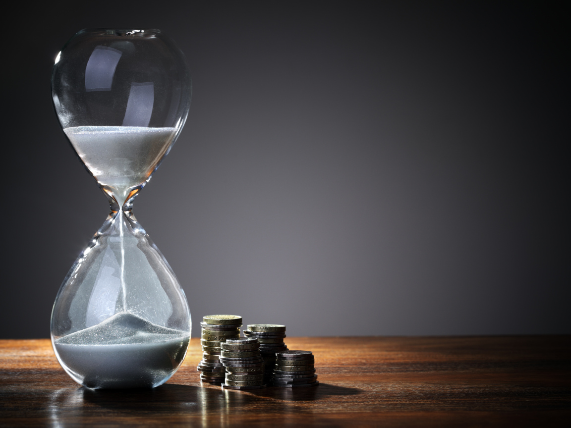 Монеты и песочные часы на столе